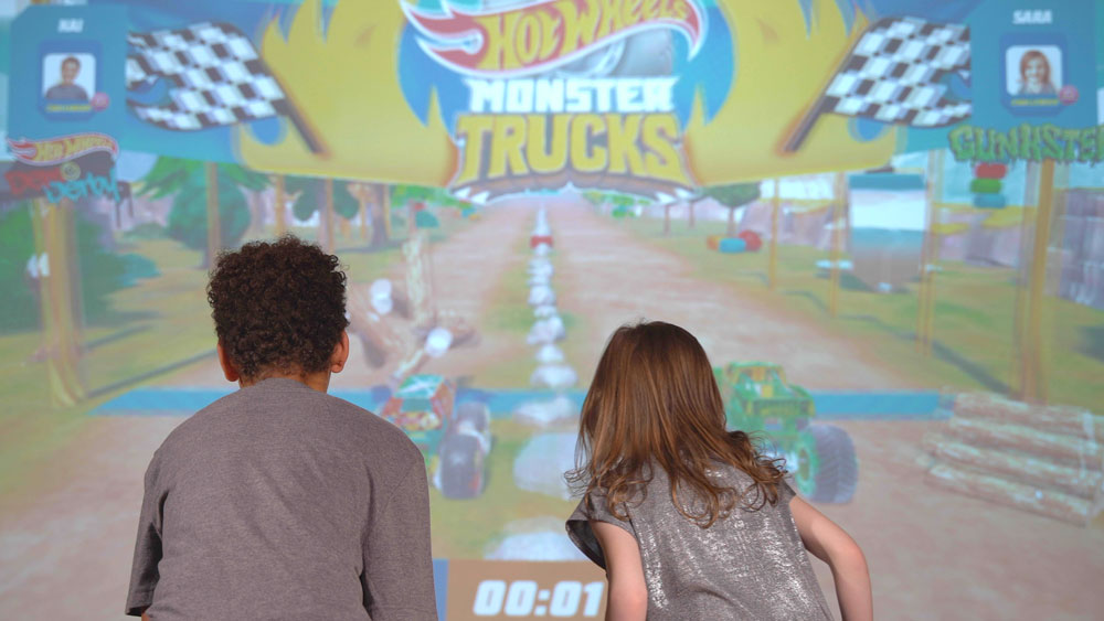 Kids racing their digital Hot Wheels Cars in the 'Smash Champ' racing game at Hot Wheels Champion Experience